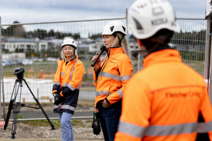 Fletcher Living Auckland North branch manager Aurelie Le Gall speaking on-site at Whenuapai, Auckland. In the background is site manager Jasmin Lawrence.